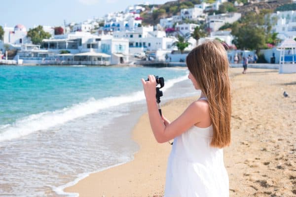The best GoPro for kids who travel Little girl on the beach with GoPro camera making photo